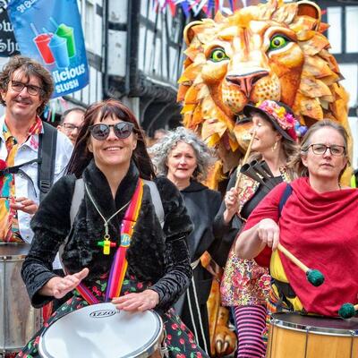 Lion puppet and samba band parade through a town