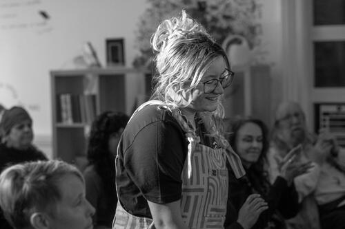 A person wearing dungarees smiling and walking up to the stage