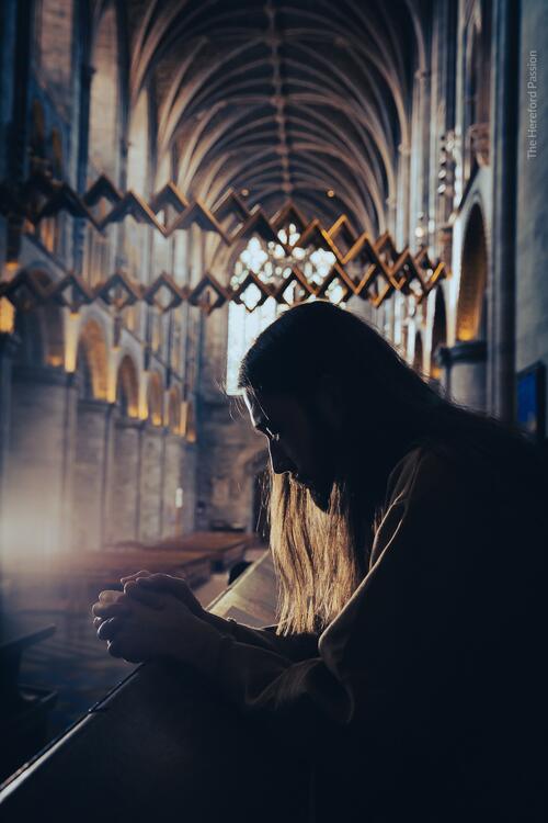 Image shows a person, who looks like Jesus, praying in a church. Photo by Caroline Potter, Hereford Cathedral