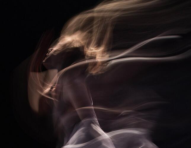 Image shows a woman wearing white but her body is blurred in movement