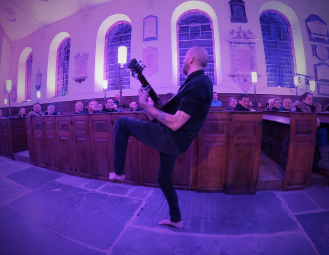 A man playing guitar in the aisle of a church