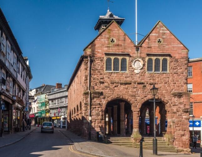 Image of Ross town centre. With the Market Hall in the centre - this is a brick building with columns and a clock on the side.